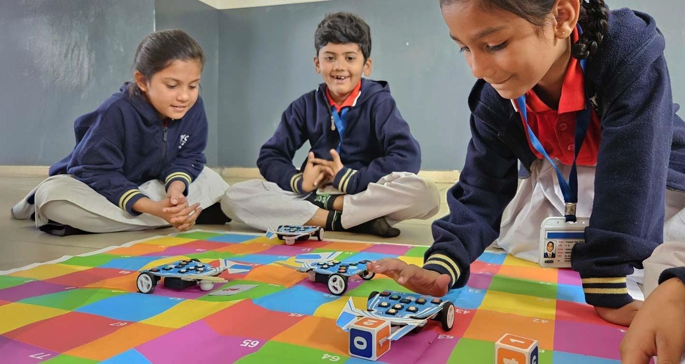 Primary school children actively engaged with educational toys and robots in classroom setting
